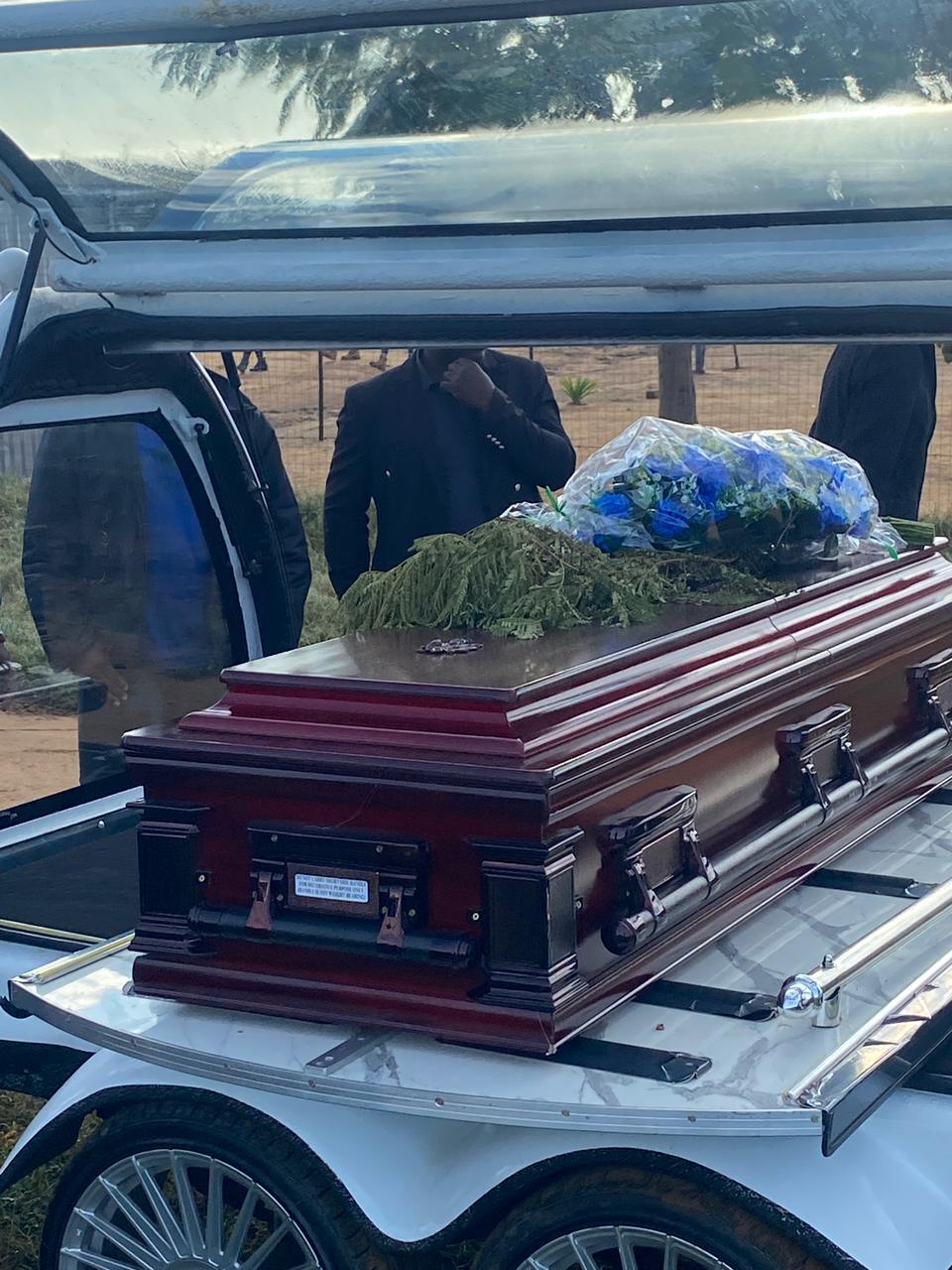 Coffin with floral tributes loaded in the hearse