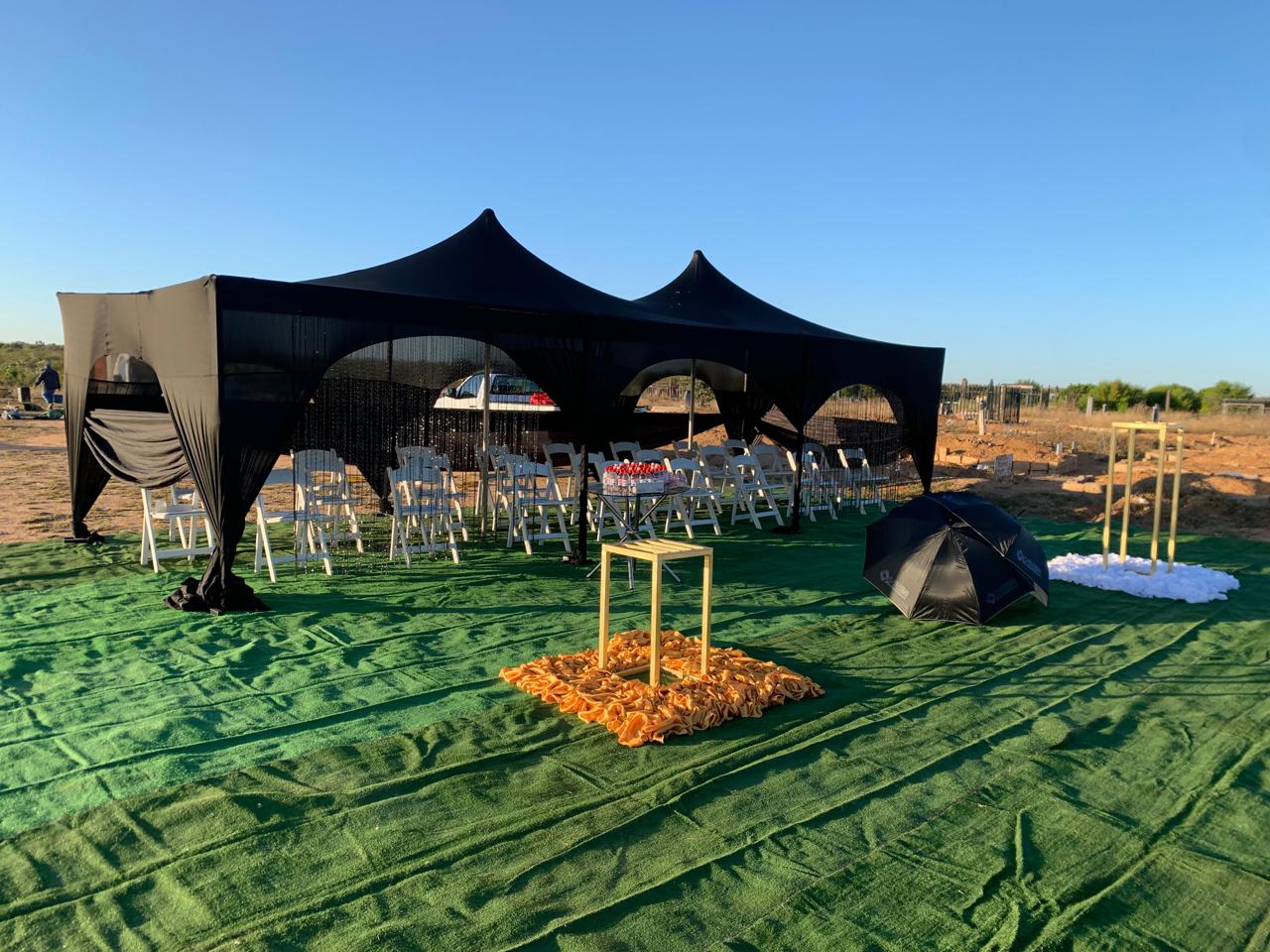 Empty graveside tent with chairs, green carpet and memorial table